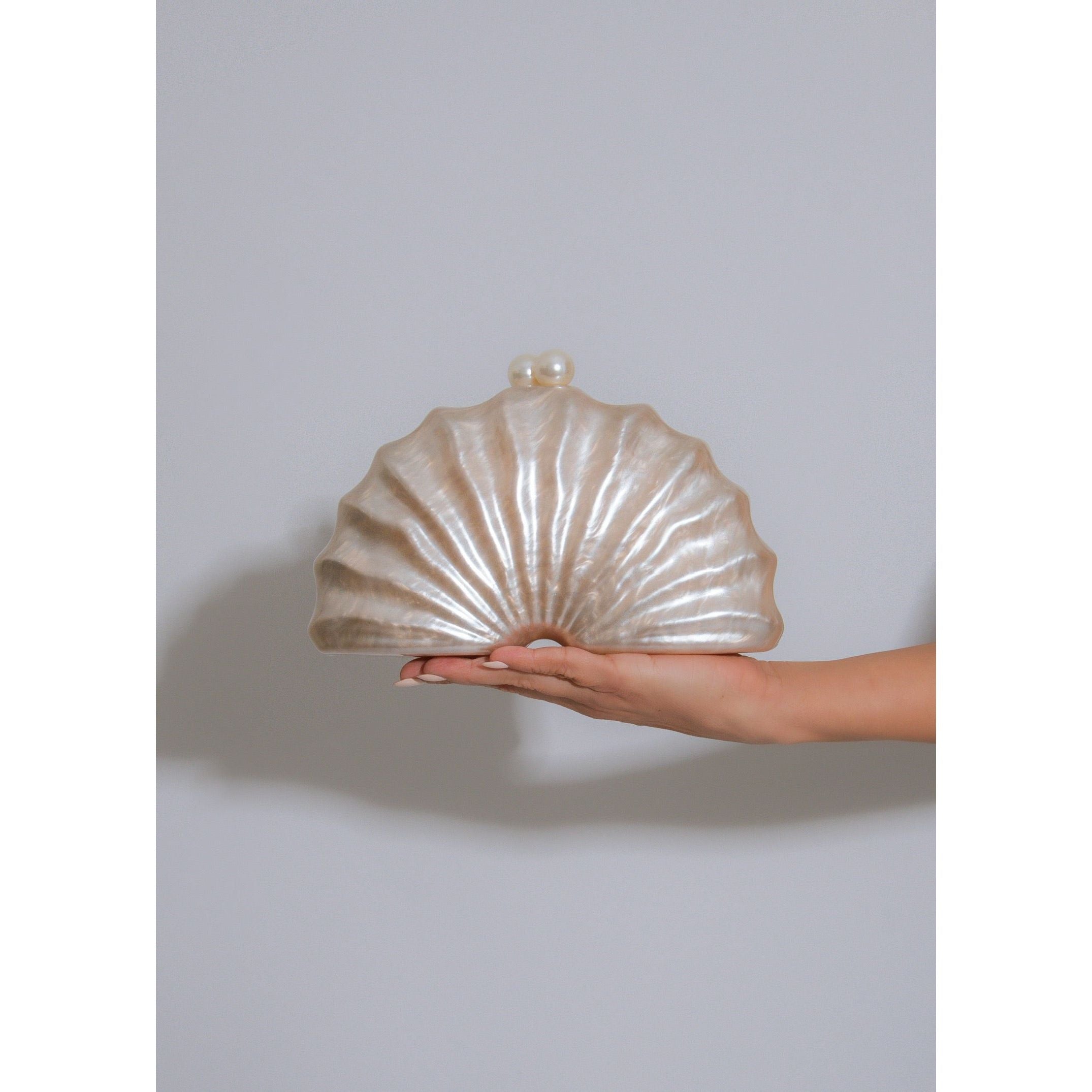 Iridescent seashell shape clutch with luminous pearl accent closure and detachable gold chain strap 