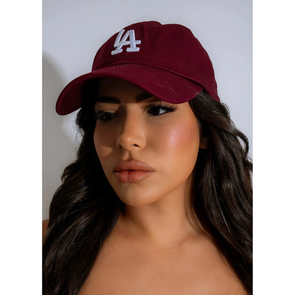 Burgundy  iconic "LA" emblem is embroidered with contrasting white stitching on  cap, featuring an adjustable strap in the back for a more personalized fit .