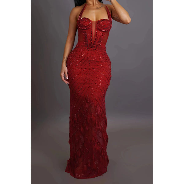  Form fitting floor length deep crimson colored maxi gown dress with illusion sweetheart halter neckline maxi gown dress is constructed with a sheer panel along the sides and back, gown is adorned with exquisite gems and elegant fringe, providing the perfect touch of shimmer.